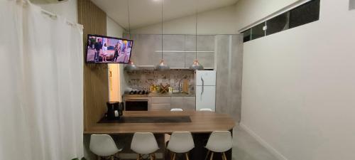 a kitchen with a table and a tv on the wall at Casa familiar - Refúgio Climatizado in Florianópolis