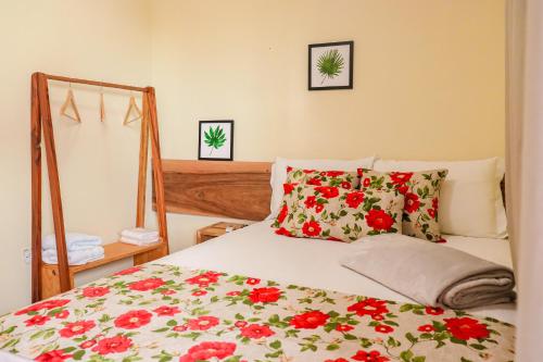 ein Schlafzimmer mit einem Bett mit roten Blumen darauf in der Unterkunft Kanoas Suites in São José da Coroa Grande
