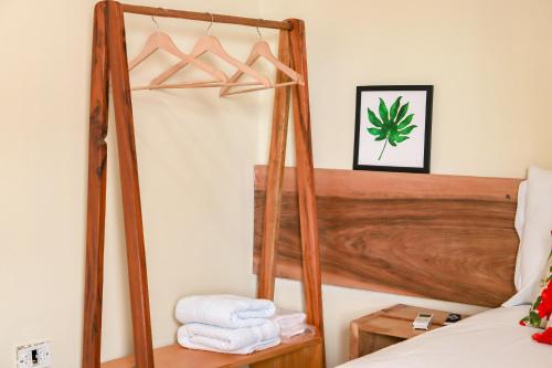 ein Schlafzimmer mit einem Bett mit Holzrahmen und Handtüchern in der Unterkunft Kanoas Suites in São José da Coroa Grande