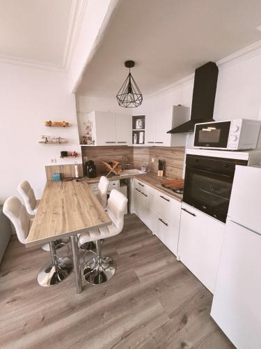 une cuisine avec une table en bois et des armoires blanches dans l'établissement Maison au cœur du village - Cocon de Provence, à Puget-sur Argens