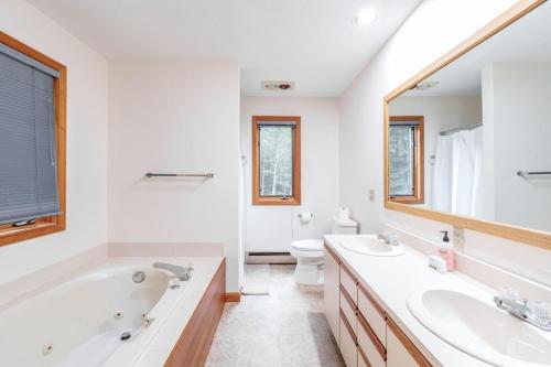 a bathroom with two sinks and a tub and a toilet at Cozy Villager Chalet w Mountain Views and Firepit in Dover