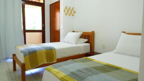 ein Zimmer mit zwei Betten und einem Fenster in der Unterkunft Villa Colibri Barra de São Miguel. in Barra de São Miguel