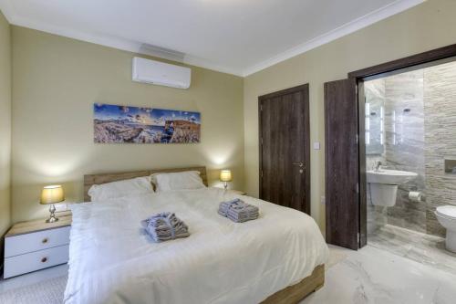 a bedroom with a large white bed and a bathroom at Penthouse, Seaview, Beautiful 2br Apt 4 in Marsaskala