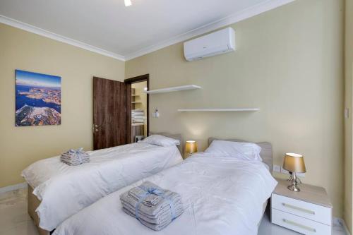 two beds in a bedroom with white sheets at Penthouse, Seaview, Beautiful 2br Apt 4 in Marsaskala