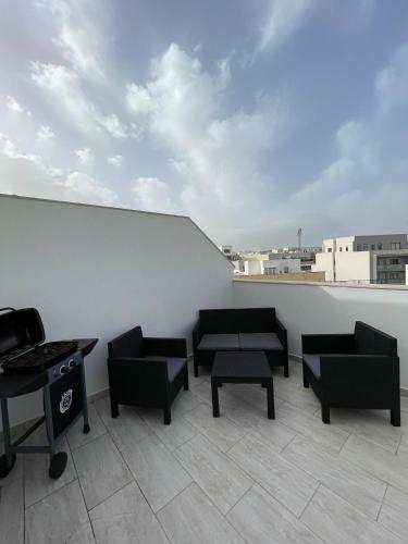 a balcony with couches and tables on a white wall at Beautiful Central Penthouse 1br in Taʼ Xbiex