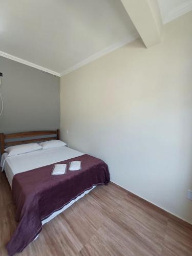 Un dormitorio con una cama con una manta morada. en Pousada Estrela Mares Suíte 210, en Cabo Frío