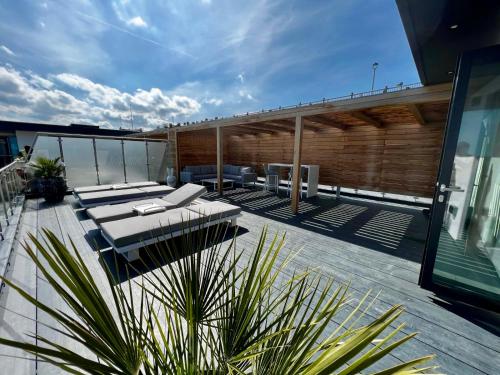 a rooftop deck with lounge chairs and tables on a building at Ramsgate Stunning Penthouse With SeaViews And Free Parking in Ramsgate