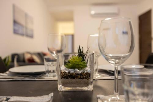 a table with wine glasses and a vase with a plant in it at Beautiful Modern Central 2br Apt in Taʼ Xbiex