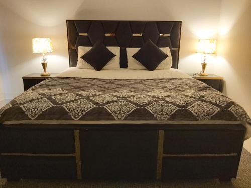 a bedroom with a large bed with two lamps at Zameen Opal in Lahore