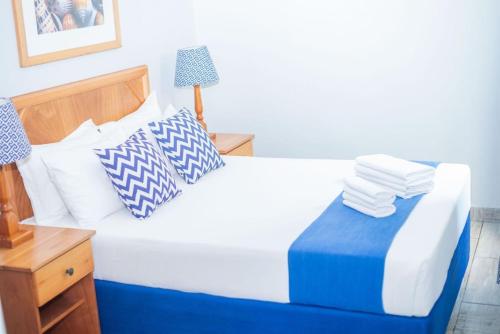 a bedroom with a bed with blue and white pillows at Durban Beachfront Bliss in Durban