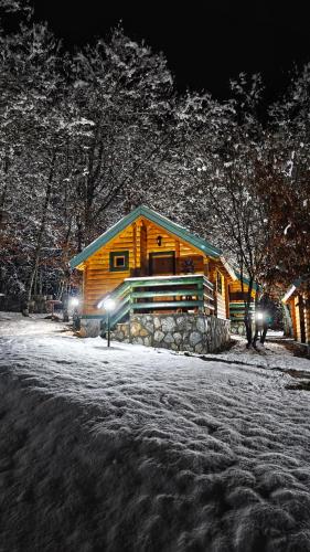 a log cabin in the snow at night at KOZAK Apartments & Restaurant in Mojkovac
