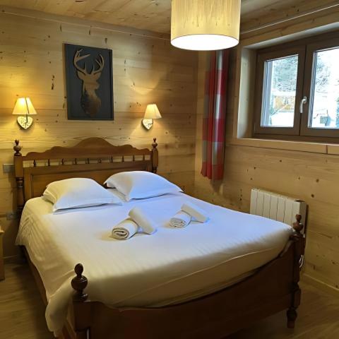 une chambre avec un lit avec des draps blancs et des oreillers dans l'établissement Chalet des Belles Roches, 14 pers, garden, sauna, à La Bresse