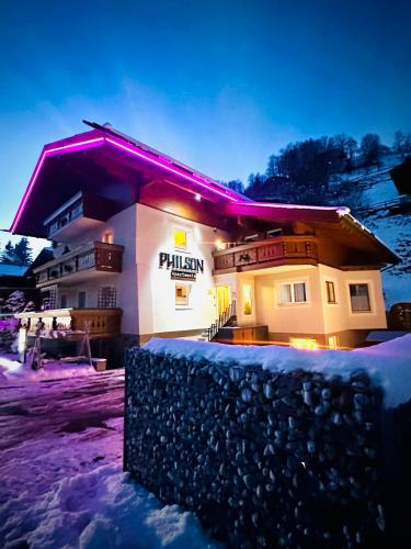 a building with purple lights on it in the snow at PHILSON Apartments in Saalbach Hinterglemm