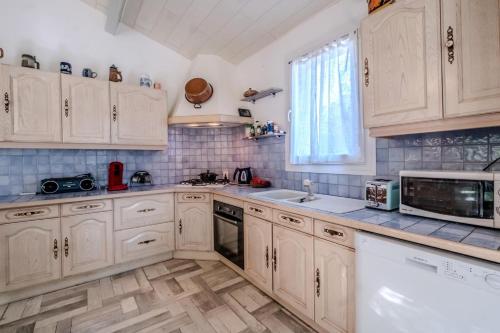 une cuisine avec des armoires blanches, un évier et un micro-ondes dans l'établissement La Pinède, à Salavas