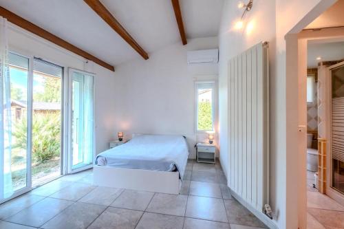 a bedroom with a bed and large windows at La Pinède in Salavas