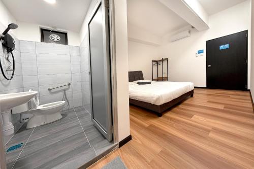 un bagno con doccia, lavandino e letto di Sofu Inn a Jelutong