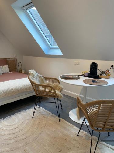 a bedroom with a bed and a table and chairs at The Conservatory a cosy private attic - Central between Ghent Antwerp Brussels & Brugge in Lokeren