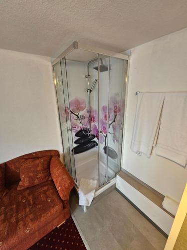 a bathroom with a glass shower with pink flowers in it at Hotel & Restaurant Krone in Rehau