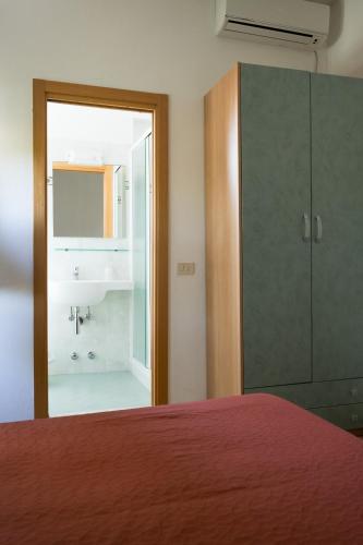 a bedroom with a bed and a bathroom with a sink at Hotel Chery in Milano Marittima