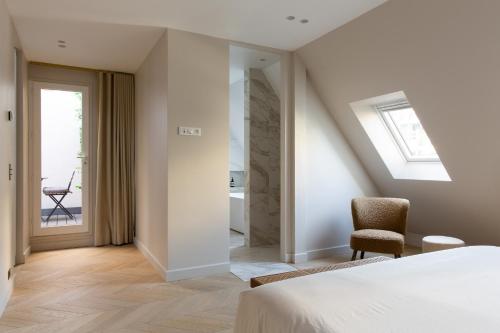 - une chambre avec un lit et une chaise ainsi qu'une salle de bains dans l'établissement HIGHSTAY - Luxury Serviced Apartments - Arc de Triomphe, à Paris