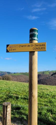a wooden sign on a wooden pole in a field at Village 17 gites, Piscine, Restaurant , 2 gites avec SPA, 3km de Conques in Conques