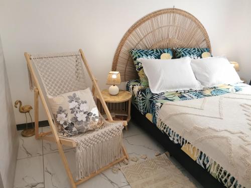 a bedroom with a wicker bed and a chair at Au Paradis des oiseaux in Saint-François