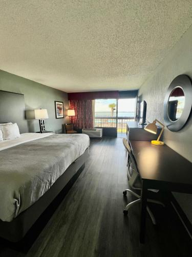 a hotel room with a bed and a desk and a window at Quality Inn & Suites Gulf Breeze Bayside near Pensacola Beach in Gulf Breeze