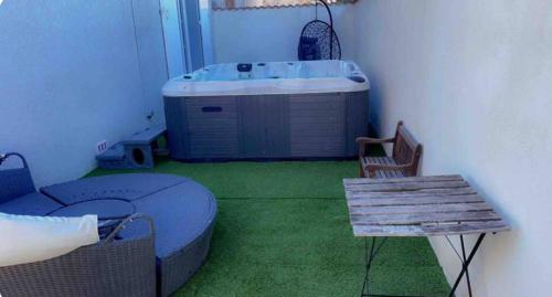 Cette chambre comprend une baignoire, une table et un banc. dans l'établissement Maison avec piscine et jacuzzi chauffée, à Jonquières-et-Saint-Vincent