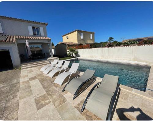 une rangée de chaises longues à côté d'une piscine dans l'établissement Maison avec piscine et jacuzzi chauffée, à Jonquières-et-Saint-Vincent