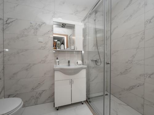 a white bathroom with a shower and a sink at Apartments 4U in Dobra Voda