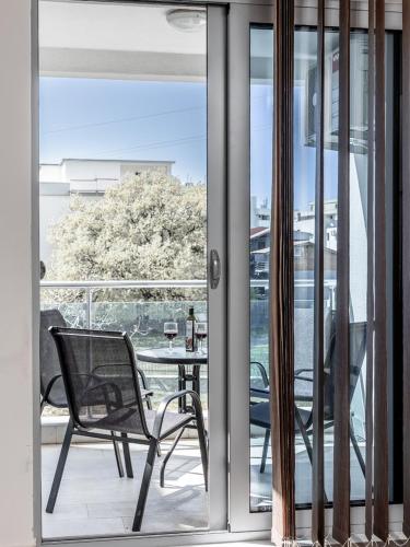 a glass door with a chair and a table on a balcony at Apartments 4U in Dobra Voda