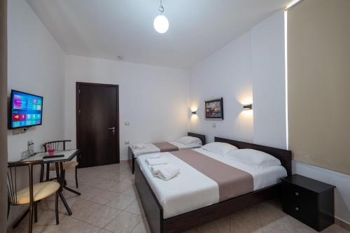 a bedroom with two beds and a desk and a television at Mariksel HOTEL in Ksamil