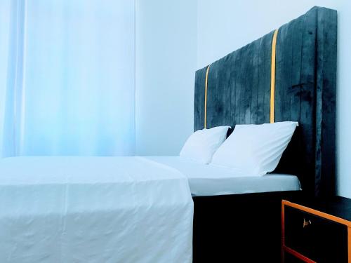 a bedroom with a white bed with a wooden headboard at La Casa De Papel Morogoro Apartment by Monalisa in Morogoro