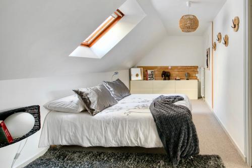 een slaapkamer met een bed en een dakraam bij Le Charmant in Lannion