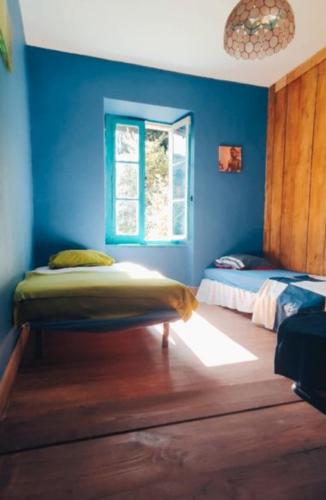 Cette chambre bleue comprend un lit et une fenêtre. dans l'établissement les Spartiates, à Seix