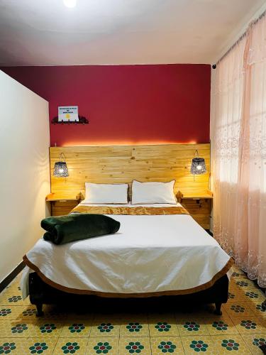 a bedroom with a large bed with a red wall at La colina in Popayan