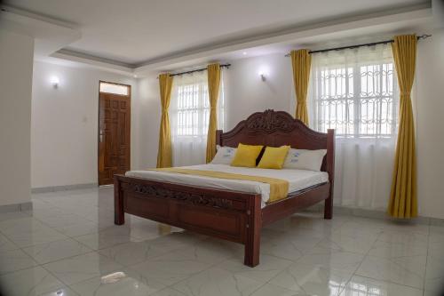 a bedroom with a wooden bed with yellow pillows at Leah's Luxury Villa in Mombasa