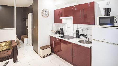 une cuisine avec des armoires rouges et un évier dans l'établissement Smart Confort 8 - Studio confort et stylé, à Troyes