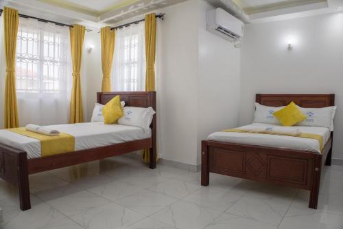 two beds in a room with yellow curtains at Leah's Luxury Villa in Mombasa
