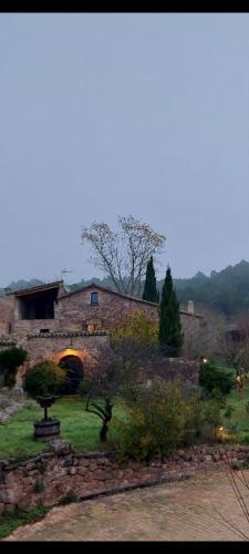 a stone building with an archway in a yard at Masia Vilatersana in Sant Llorenc Savall