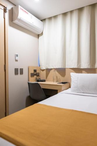 a bedroom with a bed and a desk and a window at Hotel Foresto 365 in Cali