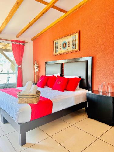 a bedroom with a large bed with red pillows at Hotel & Suites Cerro Roj0 in Tlatlauquitepec