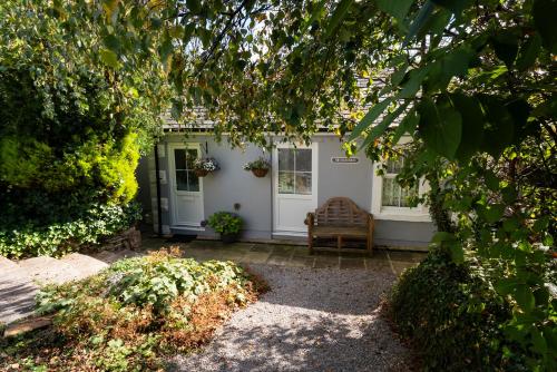 a white house with a chair in front of it at Scenery Hill Hideaways The Coach House Charming Retreat with Jacuzzi and BBQ Hut Near the Lake District in Workington