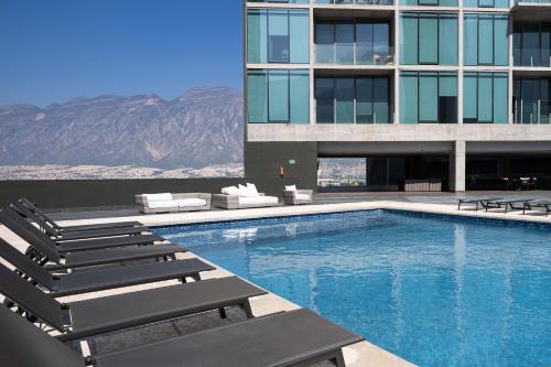 a swimming pool with lounge chairs and a building at Modern Apartments with Pool and Mountain views in Monterrey