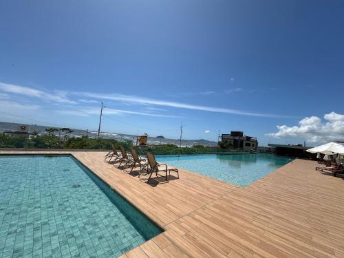 a swimming pool with chairs on a wooden deck at Summer Holiday com Piscina Climatizada - Piçarras in Piçarras