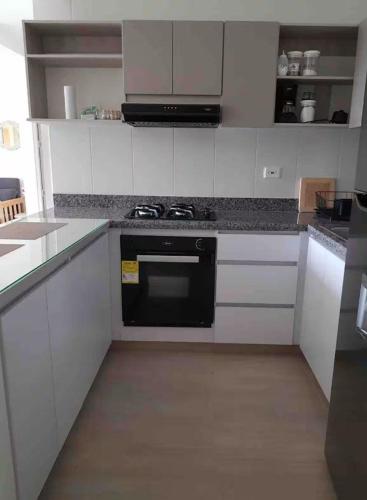 a kitchen with white cabinets and a black stove at Casa-Ámbar in Villeta
