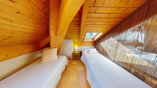 two beds in a room with wooden ceilings at Apartaments Boutique la Torreta del Llac in Puigcerdà