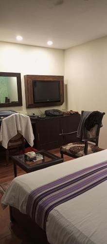 a hotel room with a bed and a flat screen tv at Hira Guest House in Karachi