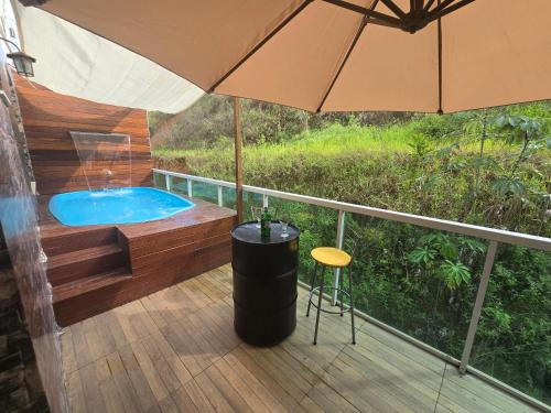 - un bain à remous sur une terrasse avec un parasol dans l'établissement Apartamento com vista para piscina, à Cataguases