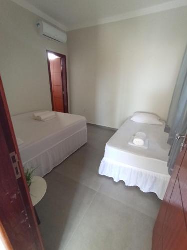 a white room with two beds and a window at Pousada Balanço do Mar in Prado